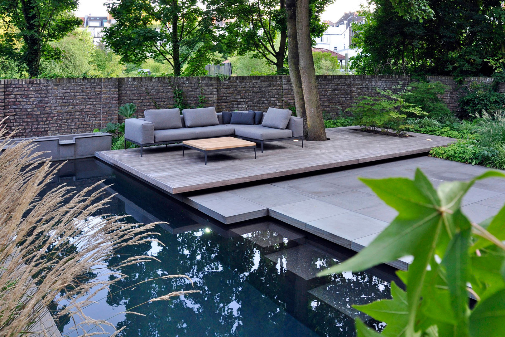Swimming Pool mit schwebendem Sitzplatz vor einer historischen Gartenmauer unter einem Großbaum Terramanus Landschaftsarchitektur Modern Garden Swimming Pool,Sitzplatz,Holzbelag,Ziegelmauer